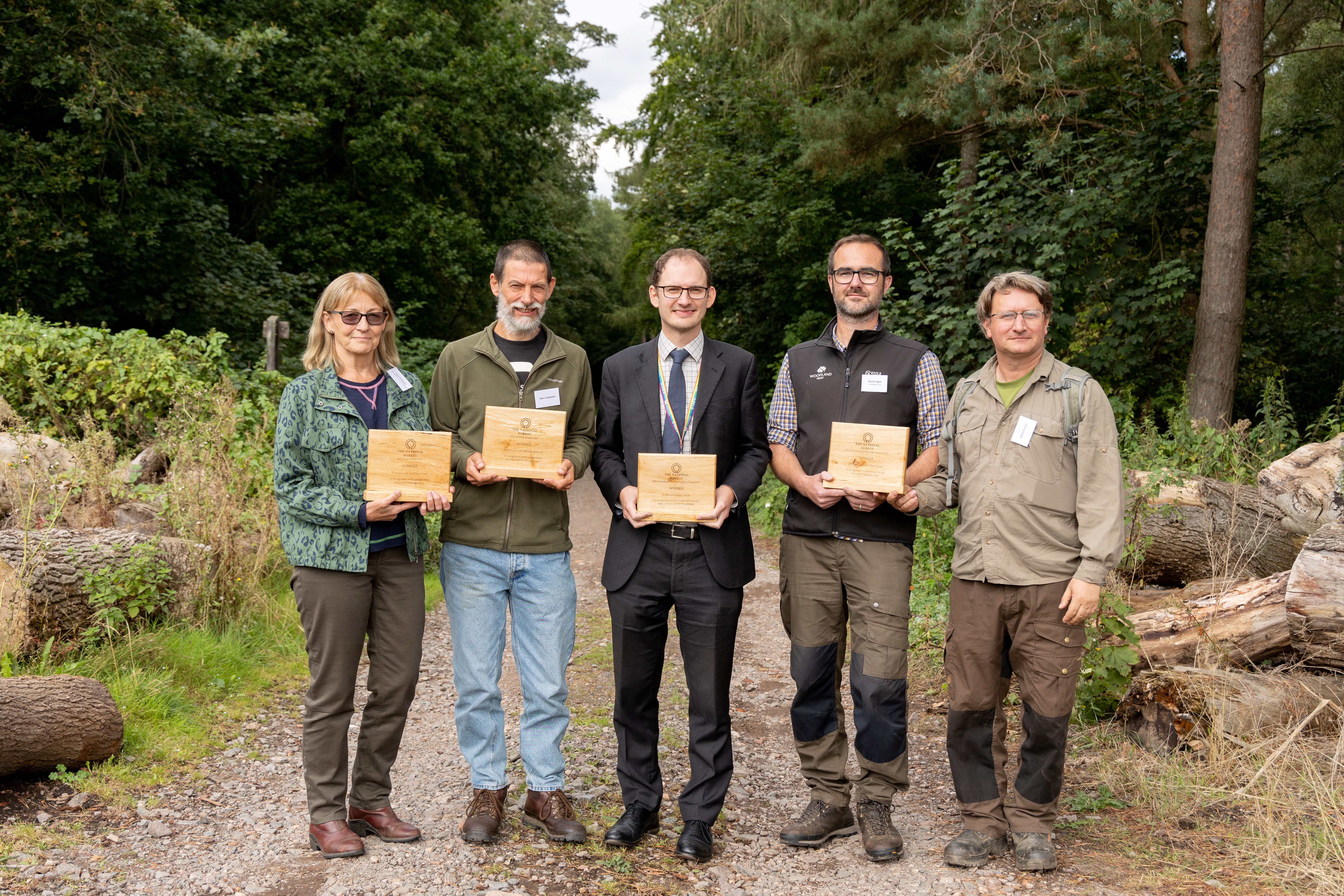 Winners of the National Forest Company Woodland Management Awards stand together holding wooden plaques.