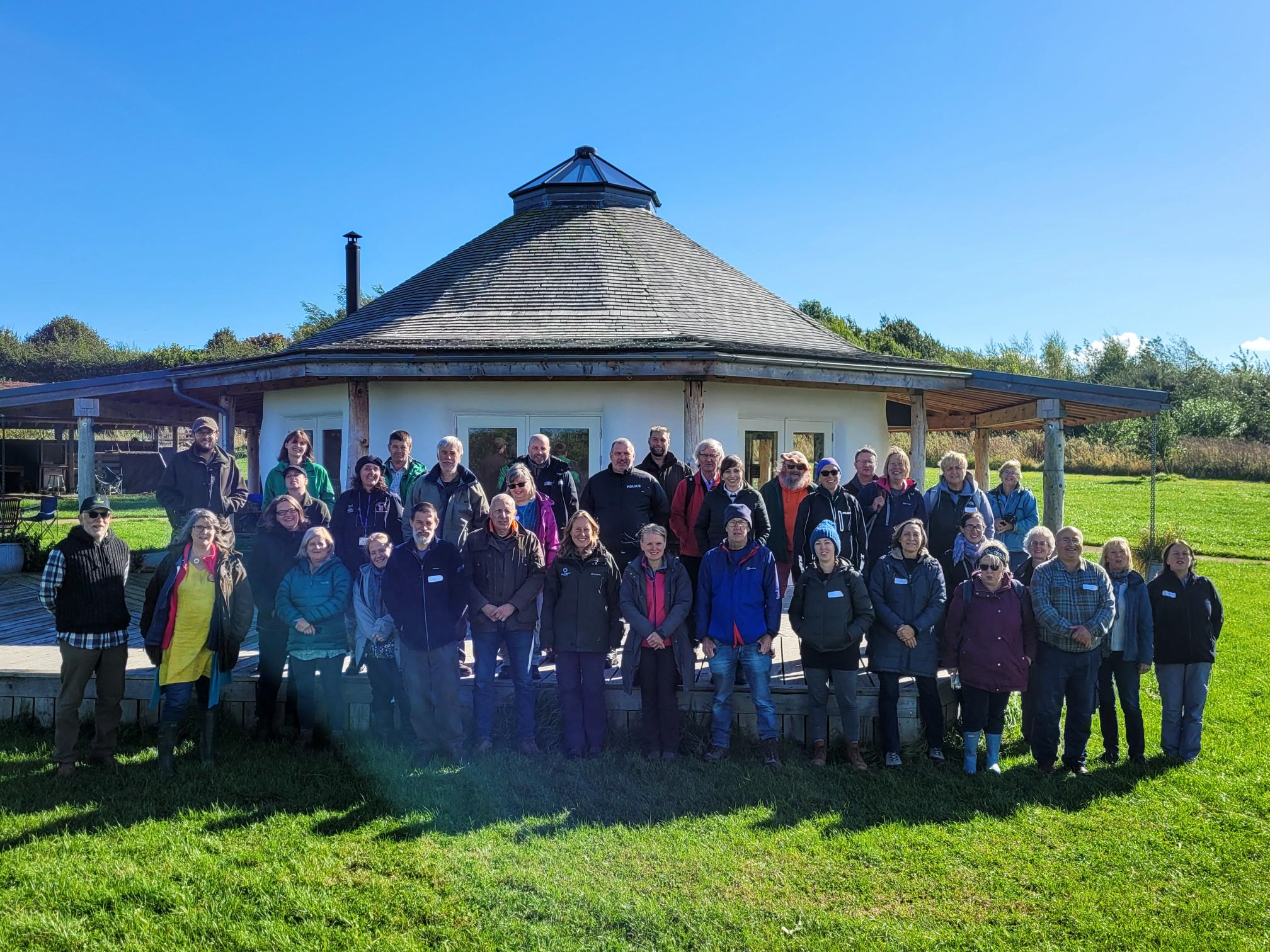 Members of the Community Woods Network stand in front of the roundhouse at Whistlewood Common